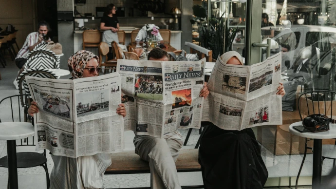 A man sitting on a bench reading a newspaper